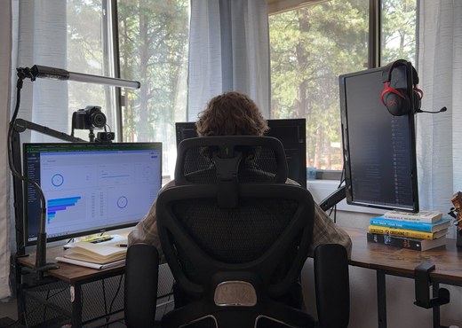 Mason at his desk with an ad-performance dashboard on the left monitor